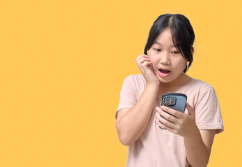 Portrait of amazed cute asian girl standing, looking at phone display with opened mouth.