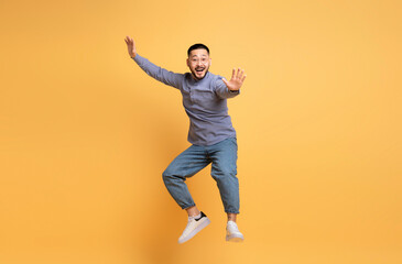 Fototapeta na wymiar Cheerful Young Asian Man Fooling Over Yellow Background