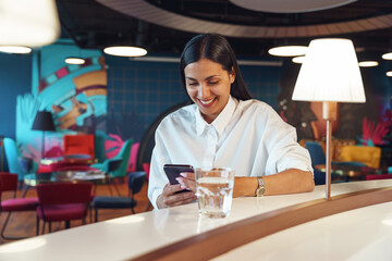 Attractive business woman looking on phone while resting in office during break time