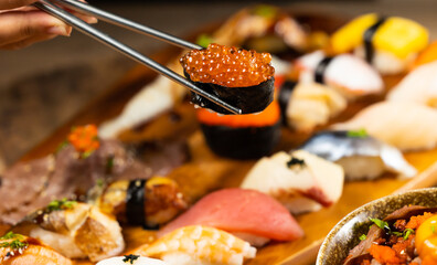 Eating sushi with chopsticks close up. Assorted japanese sushi food. sushi with tuna, crab, salmon, eel and rolls. Japanese food isolated on white background