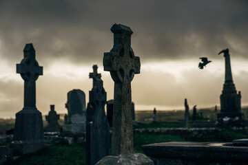 Fototapeta premium Old Cemetery in Ireland with Celtic Cross Gravestones and Birds flying