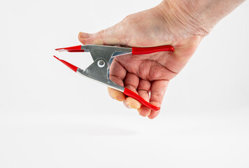 tradesman carpenter gripping a small heavy duty stainless steel and red handled portable clamp