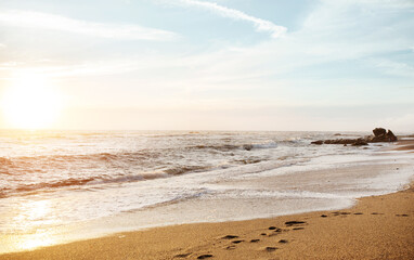 Waves, footprints on sand at ocean, blue sky with sun, outdoor, peace and quiet