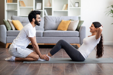 Domestic Trainings. Athletic indian couple exercising together at home, working on abs