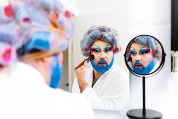 Eccentric bearded crossdressed man applying makeup before drag show