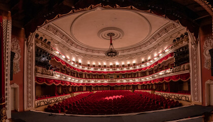 Red chairs for audience in theater. Interior of theater with sitting hall.