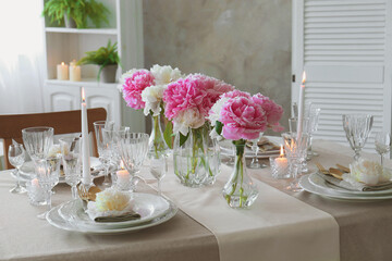 Stylish table setting with beautiful peonies and burning candles indoors