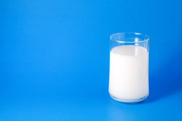 Milk in clear glass with blue background.