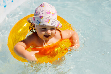 Baby girl swimming in a pool. Water park. Summer holiday activities.