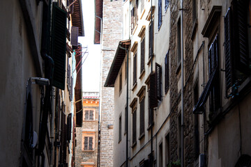 A narrow alley in Florence offers a perspective of urban life, with windows adorned with shutters...