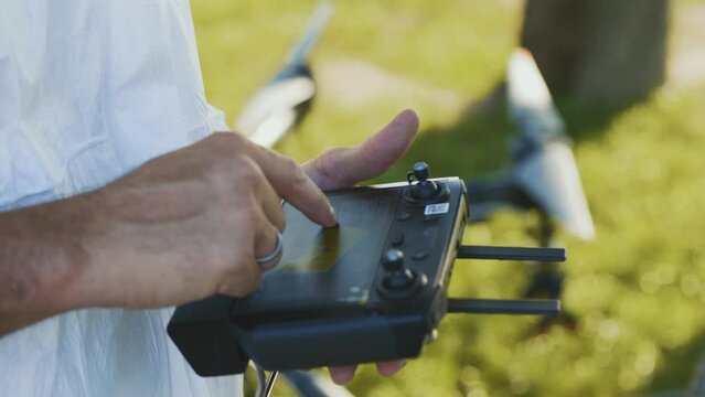 Hand of an engineer or farmer using a drone controller with a screen loads maps and enters coordinates for field spraying