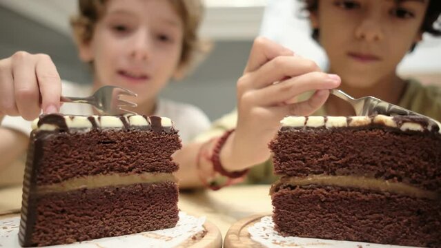 Young siblings share a homemade chocolate cake at home, indulging in a sugary treat. Unhealthy eating and excess sugar consumption, childhood diabetes, childhood obesity in Western society.