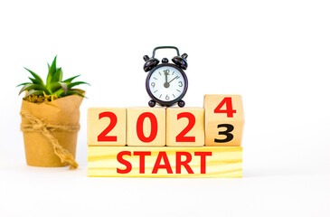 2024 start new year symbol. Businessman turns a wooden cube and changes words Start 2023 to Start...