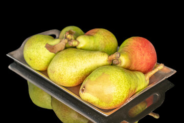 Several ripe juicy pears on a metal tray, close-up, on a black background.