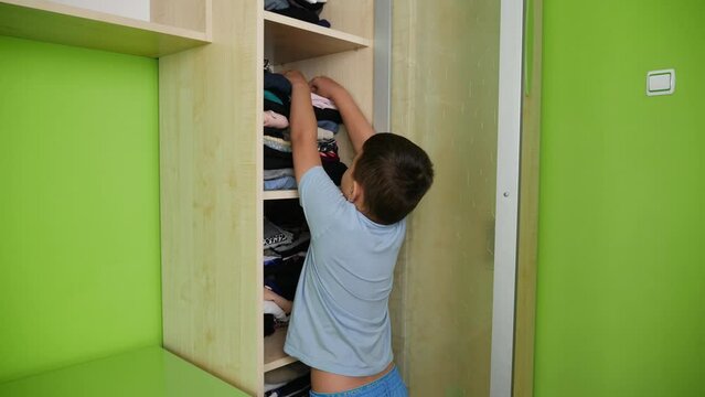 The boy puts washed and ironed clothes in the closet. Homework.