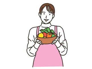 キッチンで野菜ボウルを持つエプロンの女性
