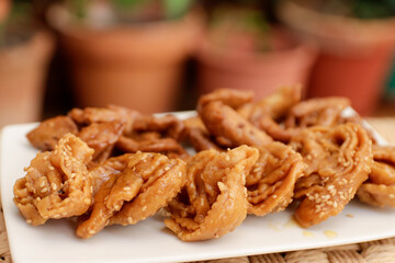 Moroccan chebakias on a white plate in a patio with plants