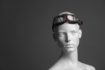Pilot concept. Female mannequin in aviation goggles on gray background with copy space.