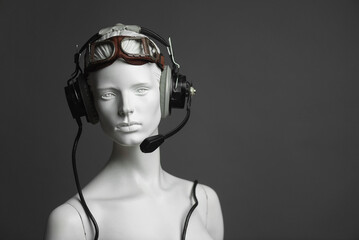 Pilot concept. Female mannequin in aviation goggles and headphones on gray background with copy space.