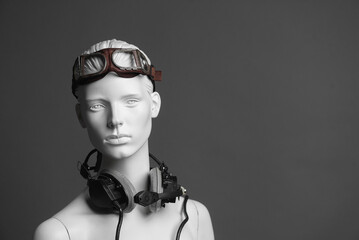 Pilot concept. Female mannequin in aviation goggles and headphones on gray background with copy space.