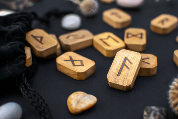 Stack of wooden runes on a black table. Scandinavian magical esoteric symbols and signs for divination and prediction of the future and destiny, esotericism concept.