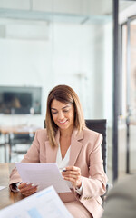 Smiling middle aged business woman account manager discussing documents doing project overview at office meeting, two professional executives holding financial papers working together. Vertical