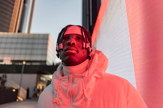 close up shot,portrait of an african american man illuminated by the red neon lights of the city - Powered by Adobe