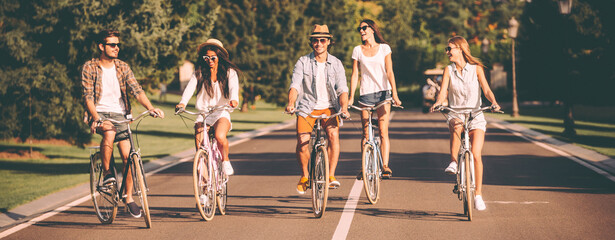 Group of beautiful young people smiling while riding bicycles together
