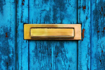 Old letterbox or mailbox slot on worn wooden blue door