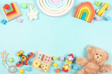 Baby kids toy frame background. Teddy bear, colorful wooden educational, sensory, sorting and stacking toys for children on light blue background. Top view, flat lay