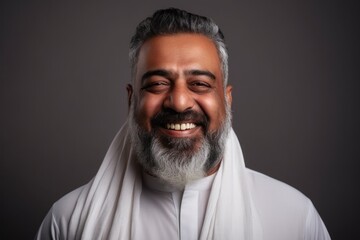 Obraz premium Medium shot portrait of an Indian man in his 50s against a minimalist or empty room background wearing hijab