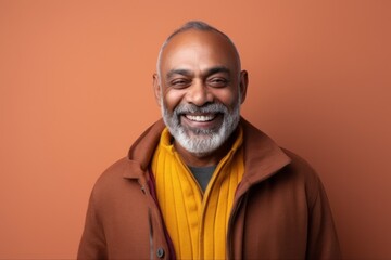 Obraz premium Medium shot portrait of an Indian man in his 50s against an abstract background wearing a chic cardigan