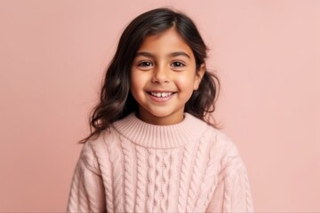 Fototapeta premium Portrait of a smiling little girl in a pink sweater on a pink background