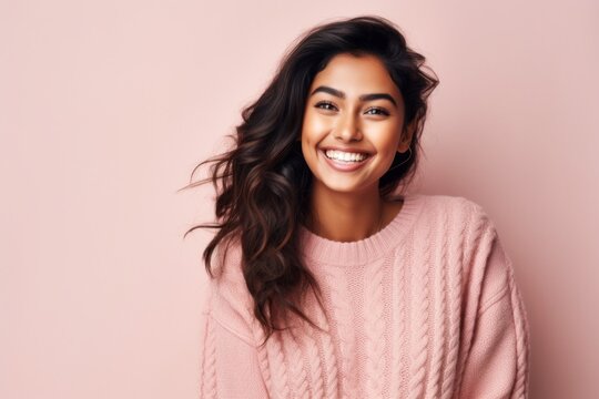 Portrait of a smiling young woman in a pink sweater on a pink background