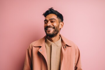 Obraz premium happy indian man in beige coat smiling at camera isolated on pink