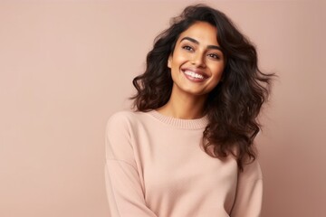 Fototapeta premium Portrait of a smiling young woman looking at camera over beige background