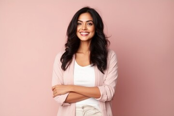 Obraz premium Portrait of a happy young woman standing with arms crossed against pink background