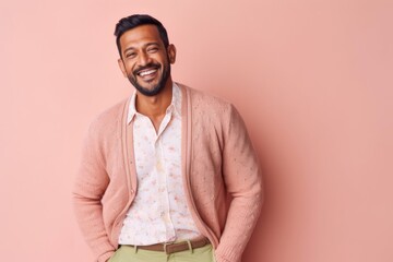 Fototapeta premium Portrait of happy indian man smiling at camera while standing against pink background