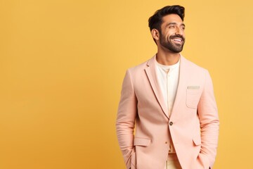 Obraz premium cheerful young indian man in pink suit looking away isolated on yellow