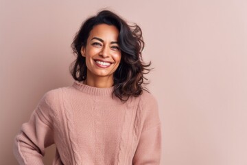 Fototapeta premium Portrait of a beautiful young woman in a pink sweater on a beige background