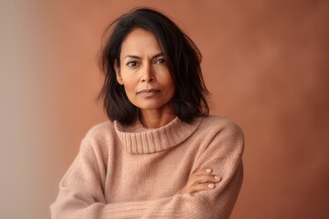 Fototapeta premium Portrait of a pensive woman looking away while standing against brown background