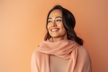 Portrait of a smiling young woman in a pink scarf on an orange background