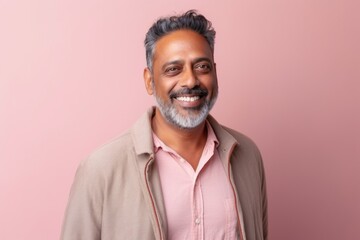 Portrait of a happy Indian man smiling at camera against pink background
