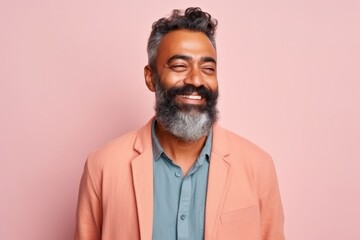 Obraz premium Handsome Indian man with beard and mustache in casual clothes posing against pink background