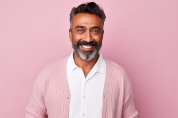 Obraz premium Handsome Indian man smiling and looking at camera while standing against pink background