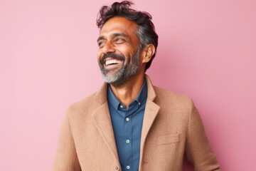 Obraz premium Portrait of a happy Indian man laughing and looking away isolated over pink background
