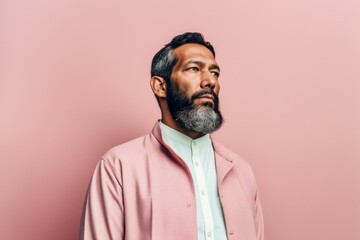 Fototapeta premium portrait of mature indian man in pink jacket looking away isolated on pink