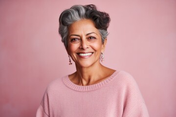 Group portrait of an Indian woman in her 50s against a pastel or soft colors background wearing a...
