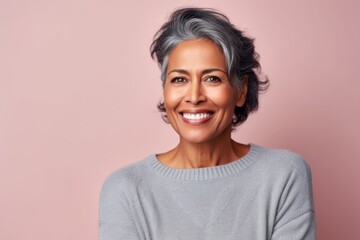Portrait of smiling mature woman looking at camera on pink background.