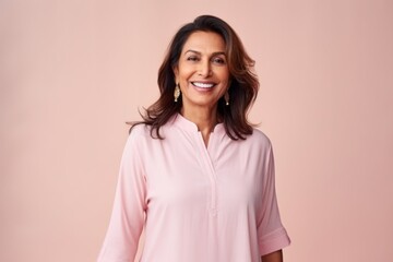 Obraz premium Portrait of a smiling middle-aged woman standing against pink background